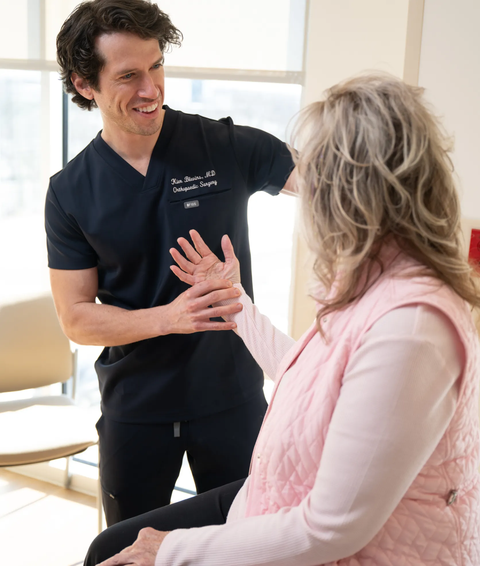 OSS orthopaedic surgeon examining an older patient’s wrist and hand