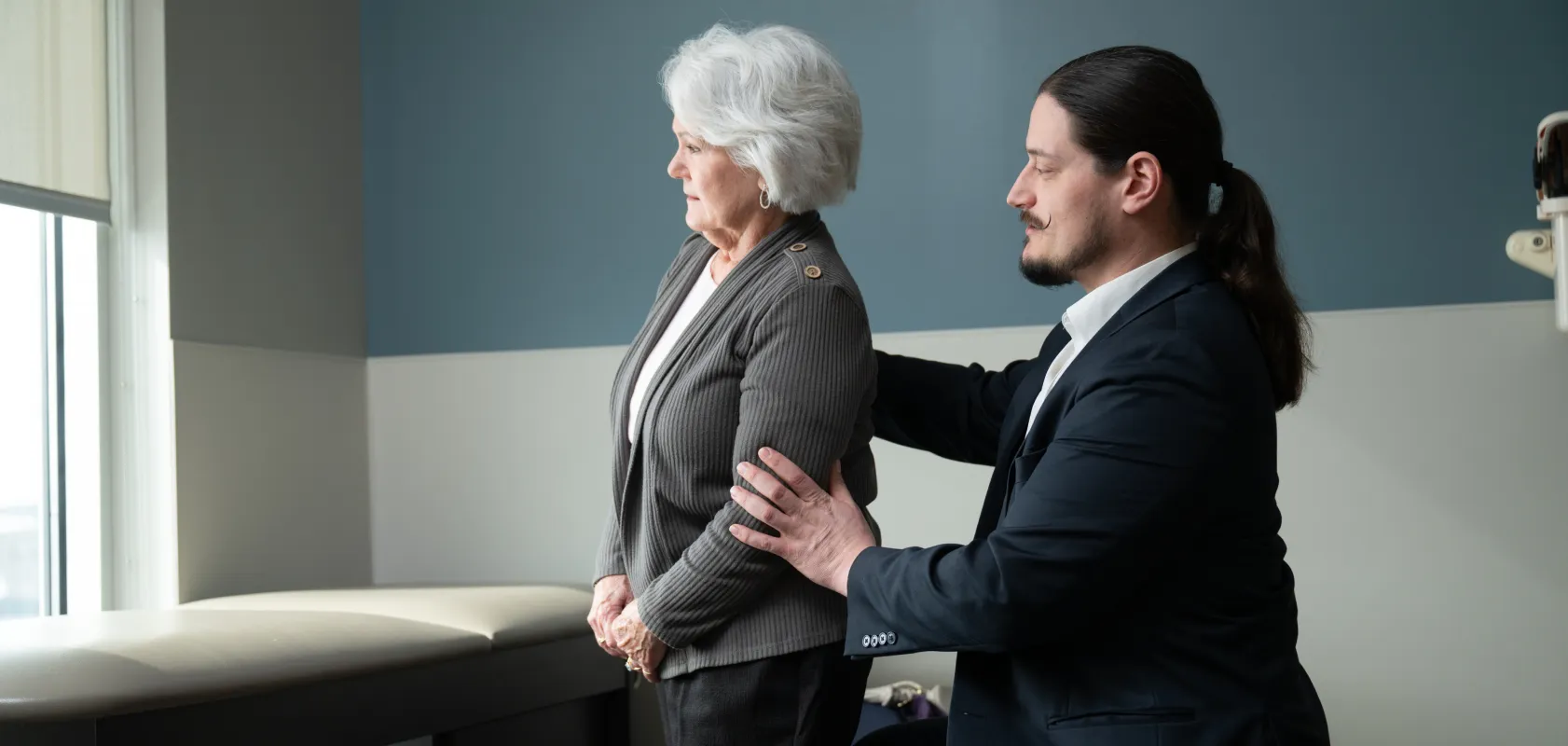 OSS Health spine specialist examining an older patient’s back and posture